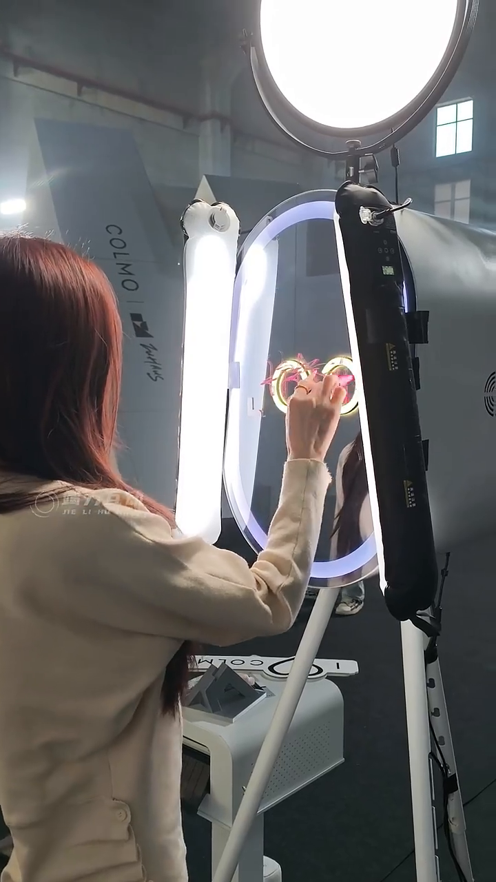 视频画面：嘉宾在镜面前书写，现场灯具与互动位置可见。 / Video frame: a guest writes at the mirror, with the on-site lighting and interaction position visible.
