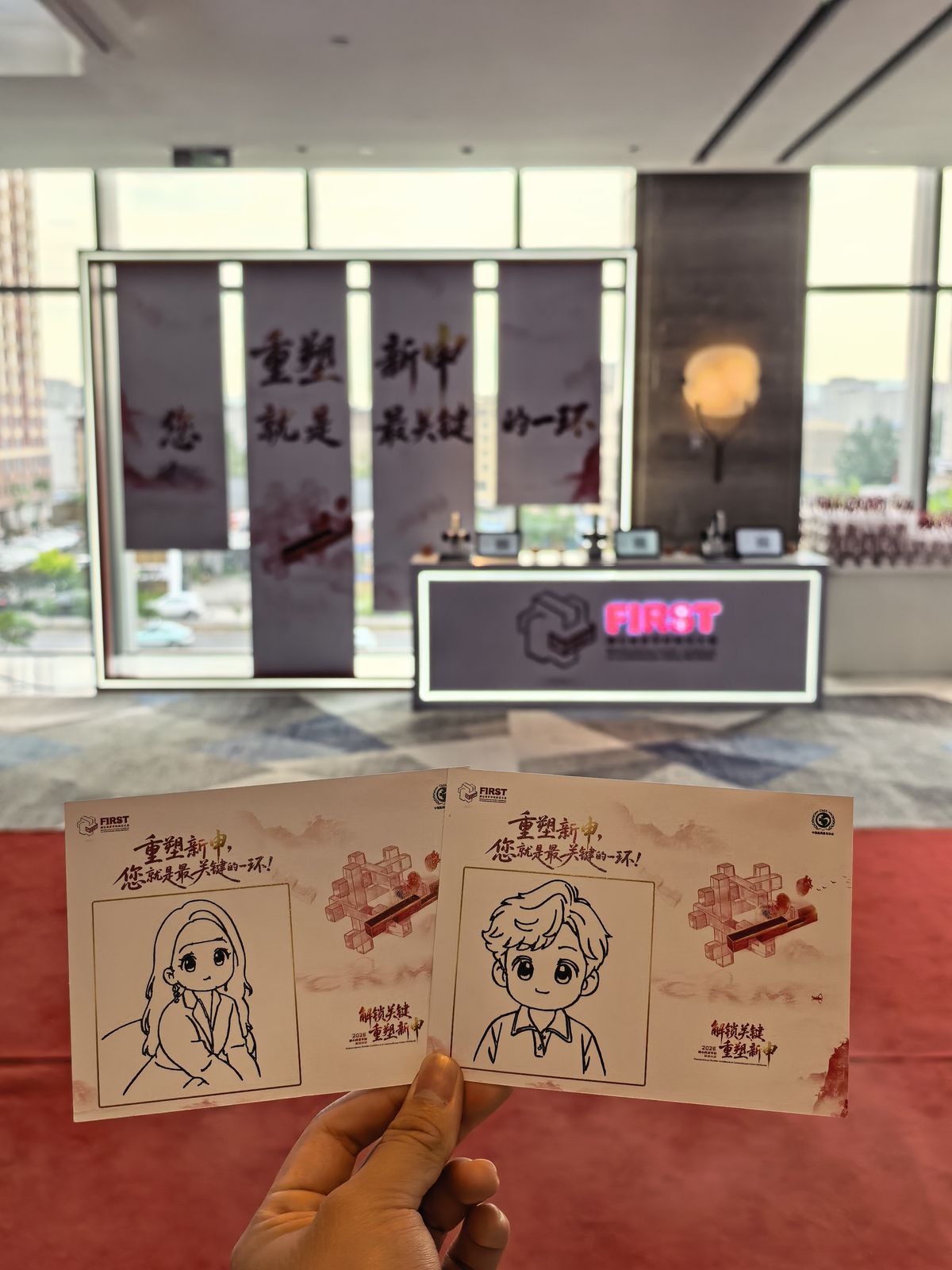 两张印有活动主视觉的卡纸画像,背景是活动主背景板 / Two branded portrait cards in front of the event backdrop